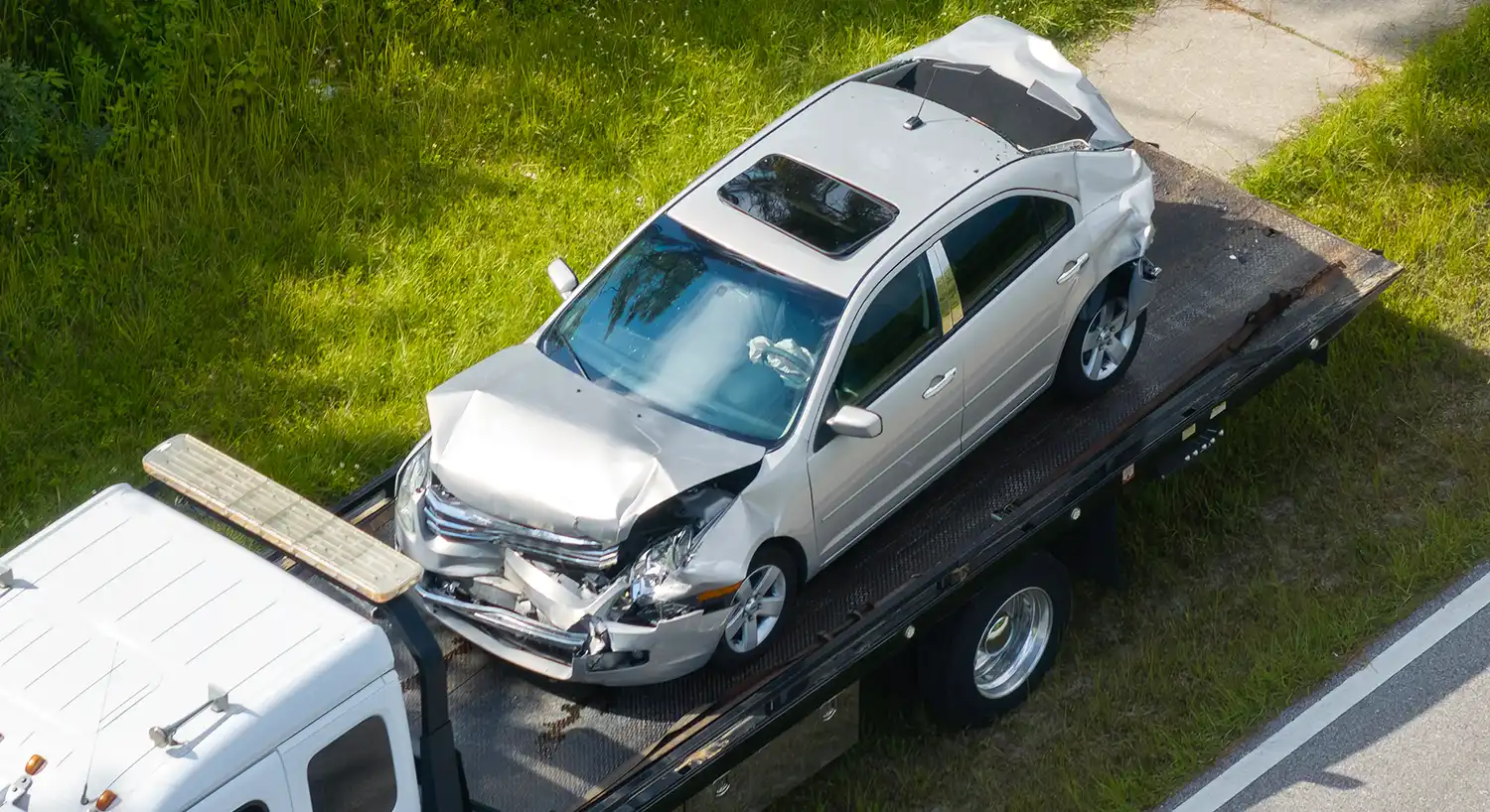 Beschädigtes Auto auf Abschleppwagen zur Autoentsorgung